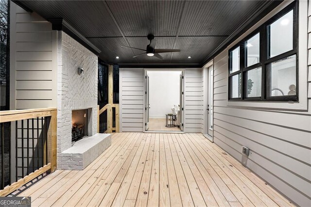 wooden deck featuring an outdoor brick fireplace and ceiling fan