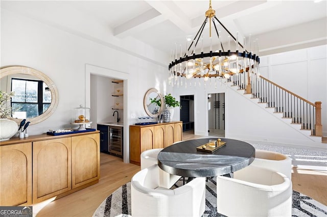 dining space featuring coffered ceiling, a notable chandelier, beamed ceiling, beverage cooler, and light hardwood / wood-style floors