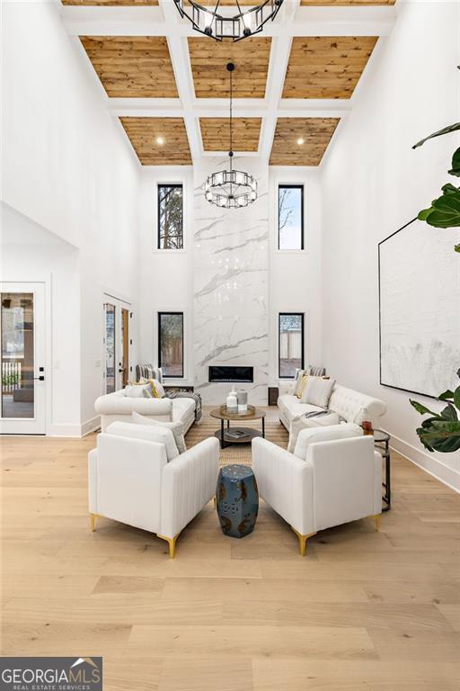 living room featuring a premium fireplace, a towering ceiling, a chandelier, and light hardwood / wood-style floors