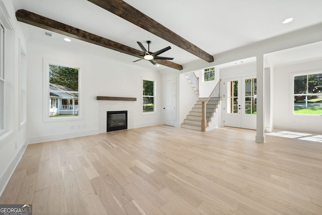 unfurnished living room featuring beamed ceiling, ceiling fan, light hardwood / wood-style floors, and french doors