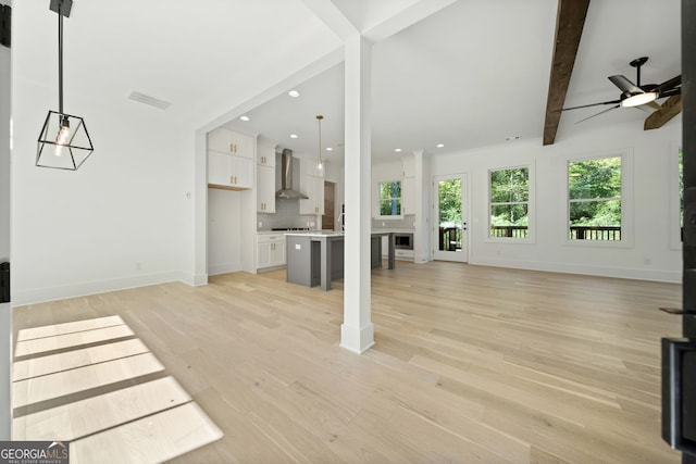 unfurnished living room featuring ceiling fan, beam ceiling, and light hardwood / wood-style flooring