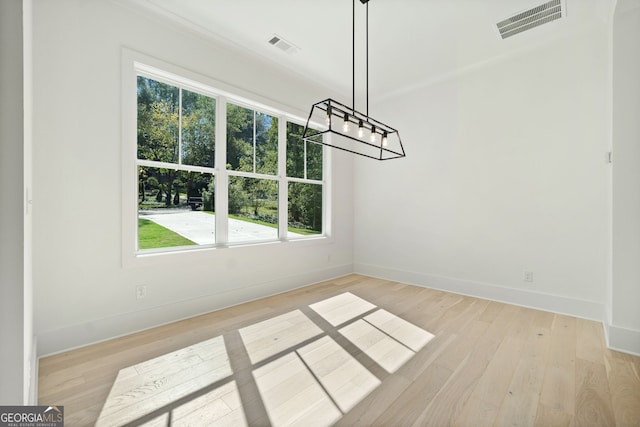 unfurnished dining area with a chandelier and light hardwood / wood-style floors