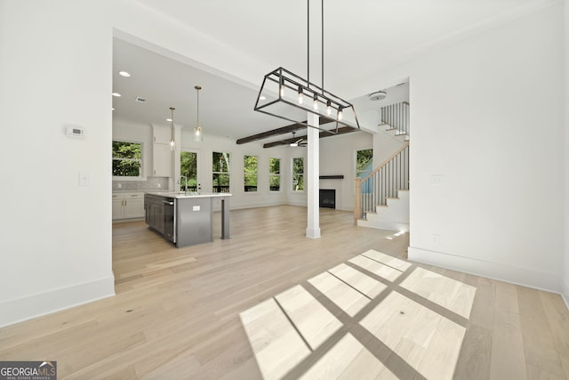 unfurnished living room featuring beamed ceiling, ceiling fan, and light hardwood / wood-style flooring