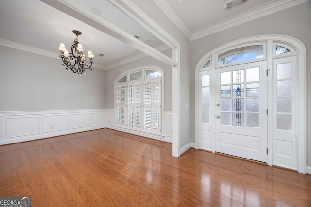 entryway featuring wood-type flooring, ornamental molding, and a chandelier