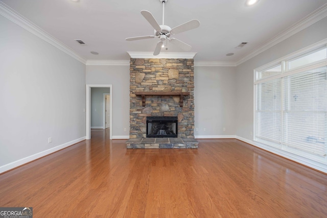 unfurnished living room with ornamental molding, a stone fireplace, wood-type flooring, and ceiling fan