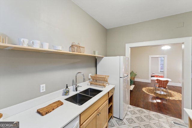 kitchen with white refrigerator, light brown cabinetry, sink, and light wood-type flooring