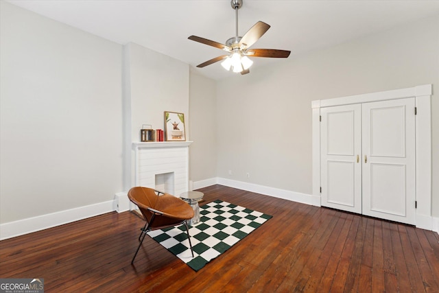 living area with dark hardwood / wood-style floors, ceiling fan, and a fireplace