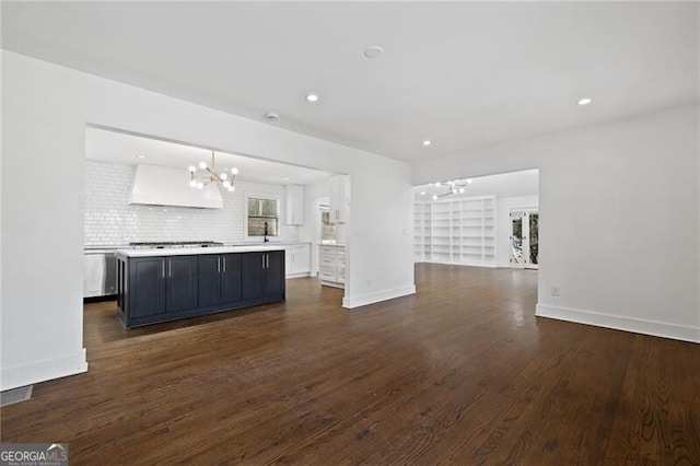 unfurnished living room featuring dark wood-type flooring and an inviting chandelier