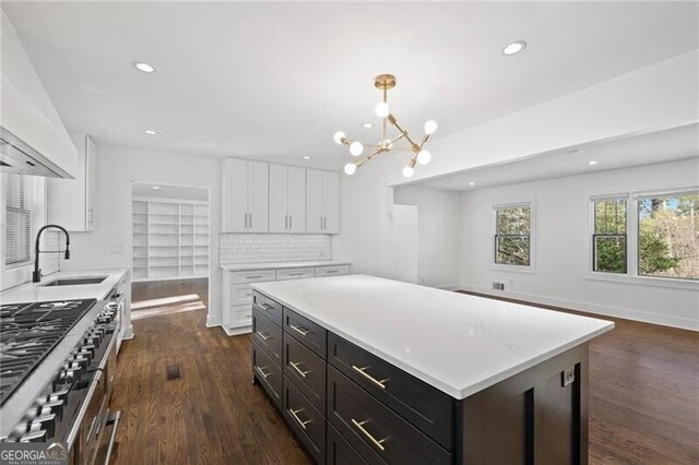 kitchen with a kitchen island, pendant lighting, sink, white cabinets, and double oven range