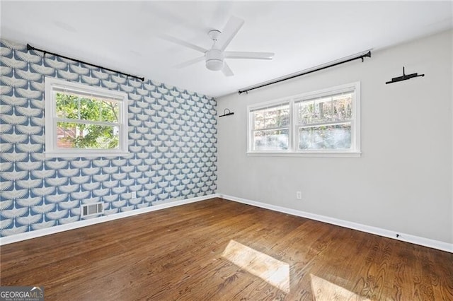 spare room with ceiling fan, a wealth of natural light, and wood-type flooring