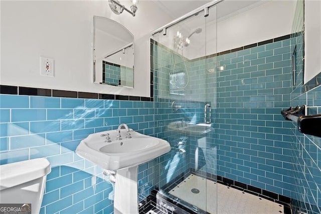 bathroom featuring a shower with door, sink, tile walls, and toilet