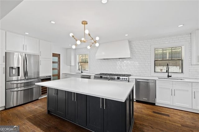 kitchen with pendant lighting, sink, premium range hood, appliances with stainless steel finishes, and a kitchen island