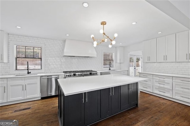 kitchen with pendant lighting, sink, dishwasher, premium range hood, and a kitchen island