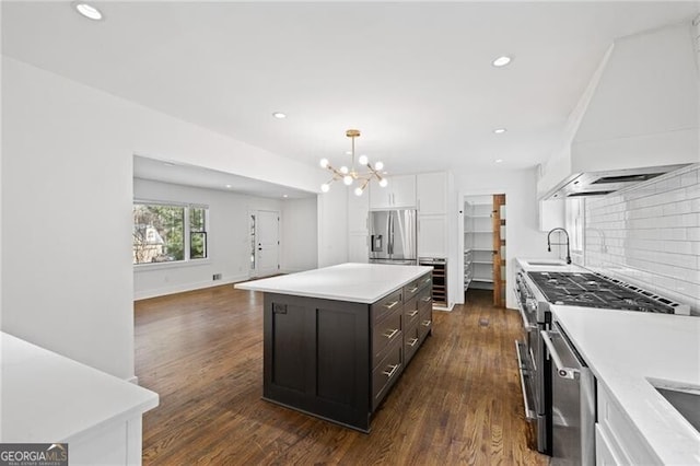 kitchen with a kitchen island, appliances with stainless steel finishes, white cabinets, hanging light fixtures, and custom range hood