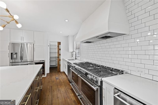 kitchen with sink, premium range hood, appliances with stainless steel finishes, light stone counters, and white cabinets