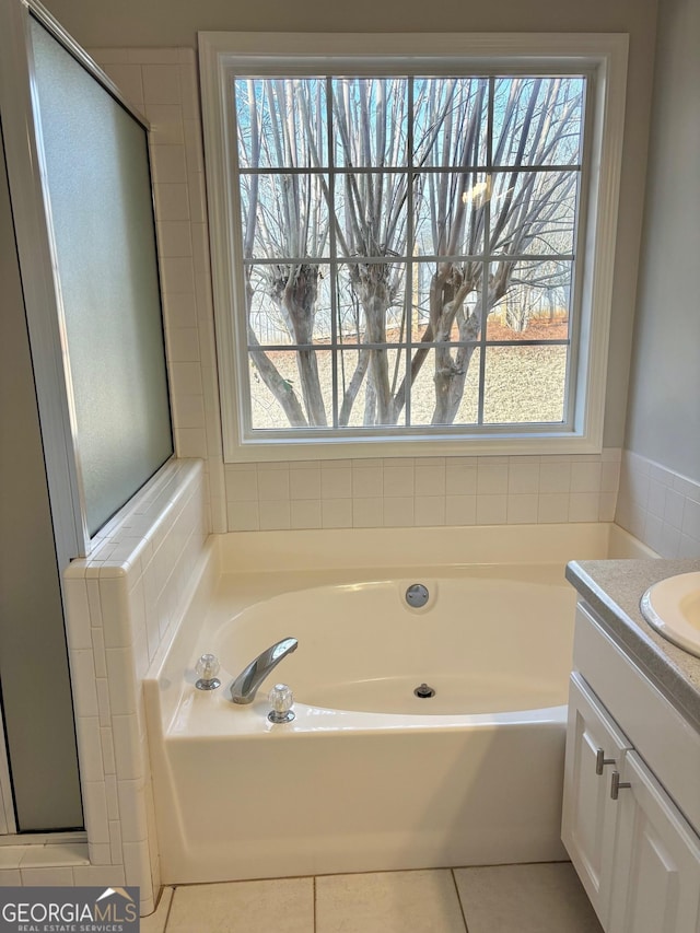 bathroom with vanity, tile patterned floors, a bathing tub, and a healthy amount of sunlight