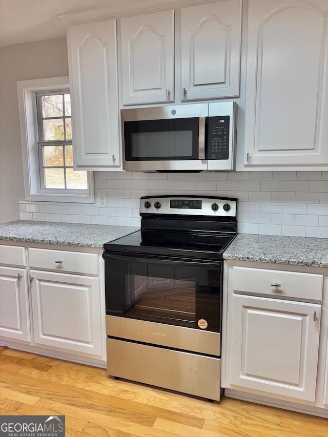 kitchen featuring stainless steel appliances, light stone countertops, and white cabinets