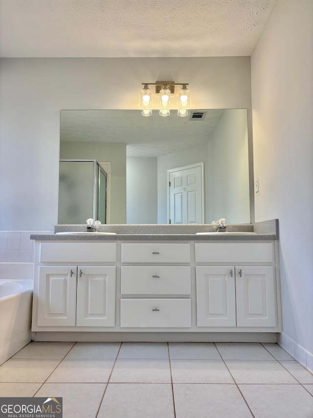 bathroom featuring tile patterned flooring, vanity, a textured ceiling, and plus walk in shower