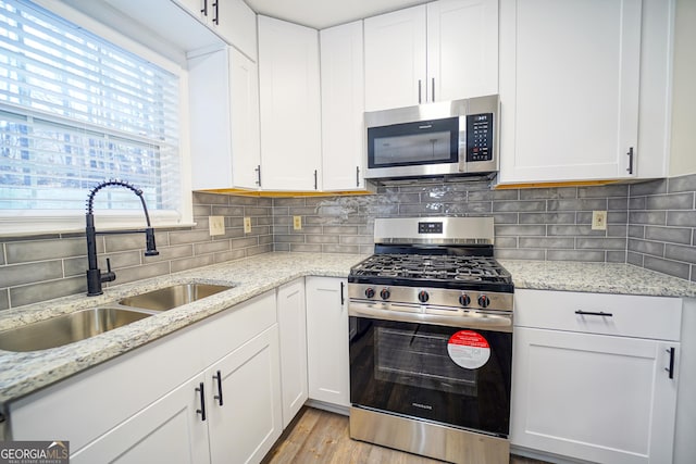 kitchen featuring stainless steel appliances, tasteful backsplash, sink, and white cabinets