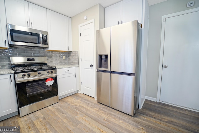 kitchen featuring light stone counters, stainless steel appliances, light hardwood / wood-style flooring, and white cabinets