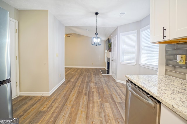 kitchen featuring decorative light fixtures, wood-type flooring, white cabinets, light stone counters, and stainless steel appliances