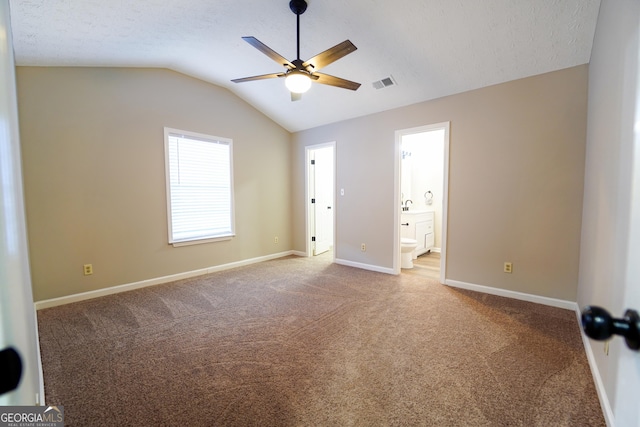 unfurnished bedroom with lofted ceiling, carpet flooring, connected bathroom, and a textured ceiling