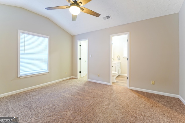 unfurnished bedroom with connected bathroom, lofted ceiling, ceiling fan, light carpet, and a textured ceiling