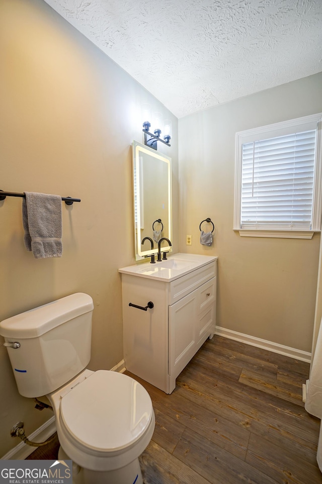 bathroom with wood-type flooring, toilet, a textured ceiling, and vanity