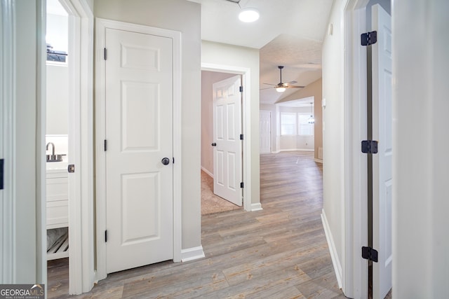 corridor with lofted ceiling and light wood-type flooring