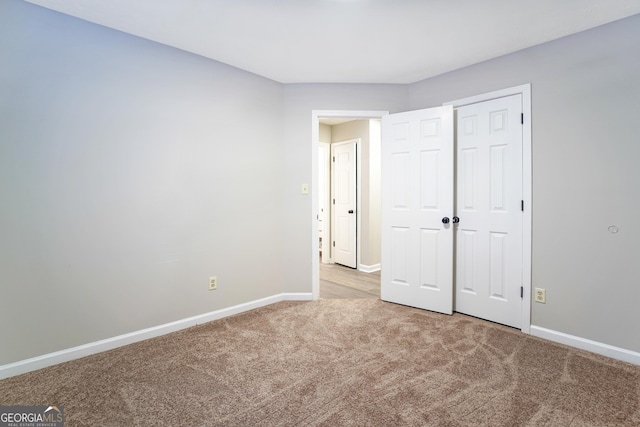 unfurnished bedroom featuring light colored carpet and a closet