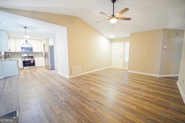 unfurnished living room featuring lofted ceiling, hardwood / wood-style floors, and ceiling fan