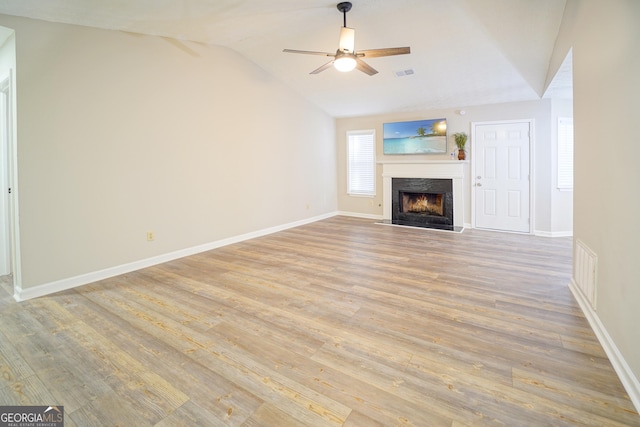 unfurnished living room featuring ceiling fan, lofted ceiling, a fireplace, and light hardwood / wood-style floors