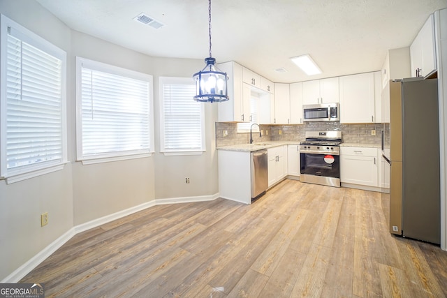 kitchen featuring tasteful backsplash, appliances with stainless steel finishes, pendant lighting, and white cabinets