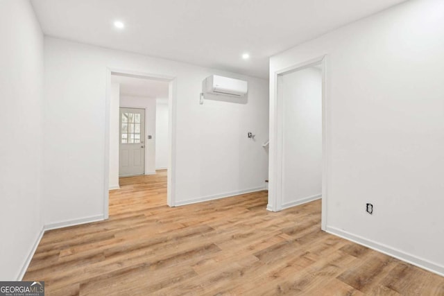 empty room featuring a wall unit AC and light hardwood / wood-style flooring