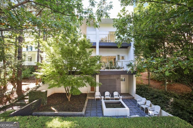 rear view of house featuring a balcony and a patio