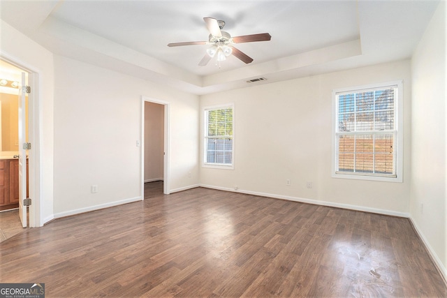 unfurnished room with ceiling fan, dark hardwood / wood-style floors, and a raised ceiling