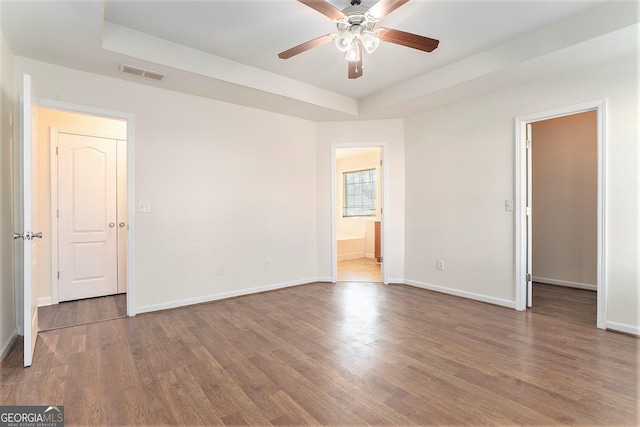 spare room with dark wood-type flooring, ceiling fan, and a tray ceiling