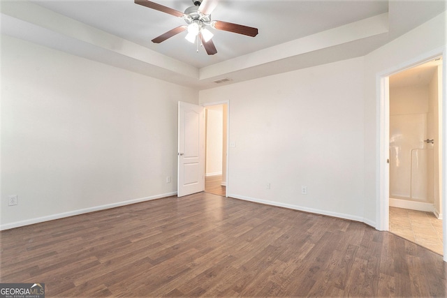 spare room featuring dark hardwood / wood-style flooring, a raised ceiling, and ceiling fan