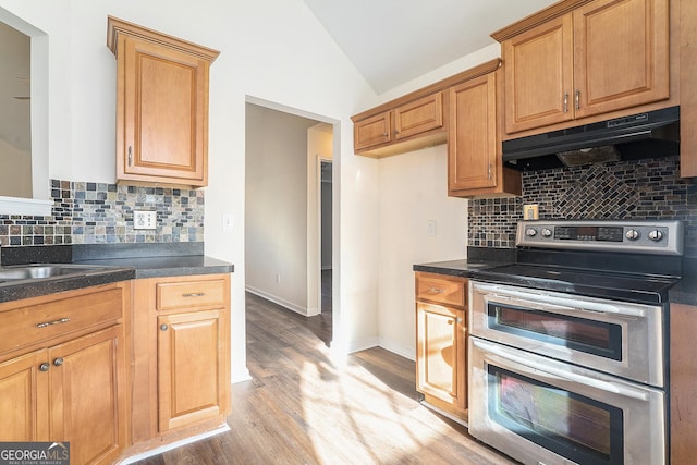 kitchen featuring vaulted ceiling, tasteful backsplash, sink, range with two ovens, and light hardwood / wood-style floors