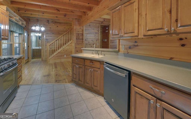 kitchen with sink, hanging light fixtures, wooden walls, stainless steel appliances, and light tile patterned flooring