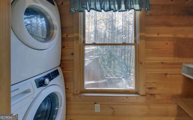 laundry room featuring stacked washer / drying machine and wooden walls