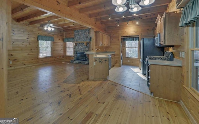 kitchen featuring a kitchen bar, range with gas cooktop, light hardwood / wood-style flooring, wooden walls, and a fireplace