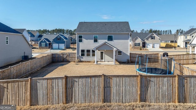 rear view of house with central AC and a trampoline