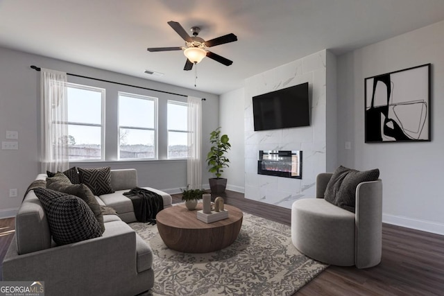 living room with ceiling fan, dark wood-type flooring, and a fireplace