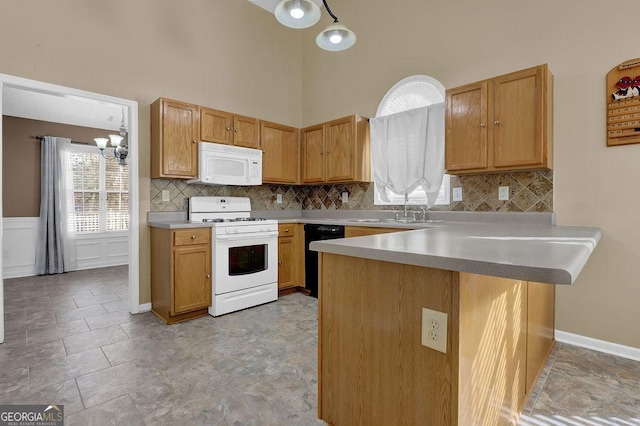 kitchen featuring tasteful backsplash, white appliances, kitchen peninsula, and sink