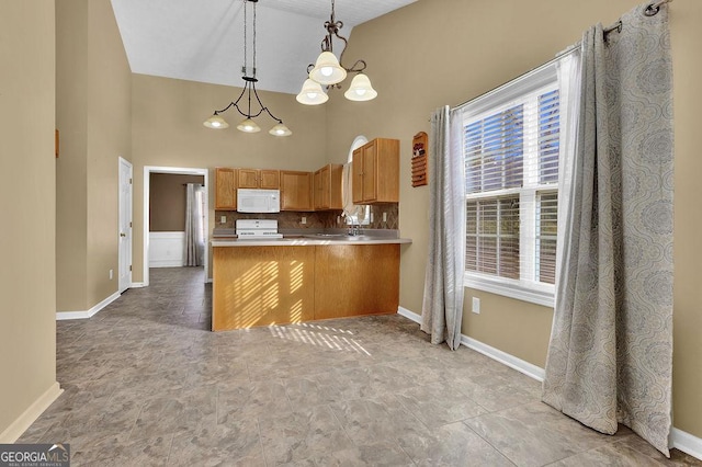 kitchen with white appliances, high vaulted ceiling, a notable chandelier, decorative light fixtures, and kitchen peninsula