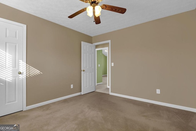 spare room featuring ceiling fan, light carpet, and a textured ceiling