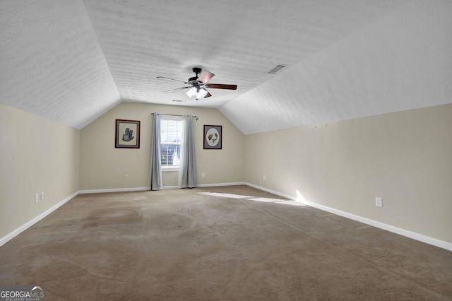 additional living space featuring ceiling fan, vaulted ceiling, a textured ceiling, and carpet