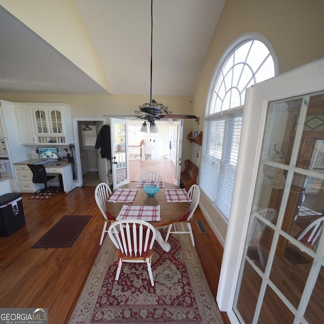 dining space featuring hardwood / wood-style floors, high vaulted ceiling, and ceiling fan