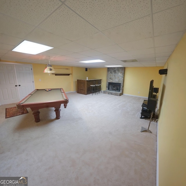 recreation room with a fireplace, a paneled ceiling, a wall unit AC, and carpet flooring